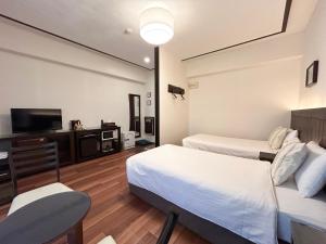 um quarto de hotel com duas camas e uma televisão de ecrã plano em Pension Sunset Beach em Nakijin