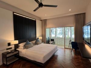 a bedroom with a large bed with a ceiling fan at Lone Pine, Penang, a Tribute Portfolio Resort in Batu Ferringhi