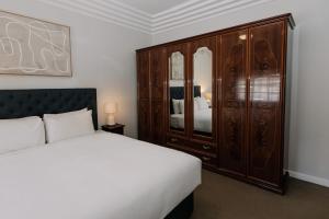 a bedroom with a bed and a large wooden cabinet at Apartments on Morrow in Wagga Wagga