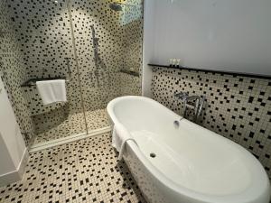 a bathroom with a white tub and a shower at Lone Pine, Penang, a Tribute Portfolio Resort in Batu Ferringhi