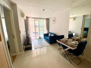 uma sala de estar com uma mesa e um sofá azul em Grand Caribbean Condo Resort Pattaya 19 floor em South Pattaya