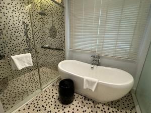 a bathroom with a shower and a tub and a sink at Lone Pine, Penang, a Tribute Portfolio Resort in Batu Ferringhi