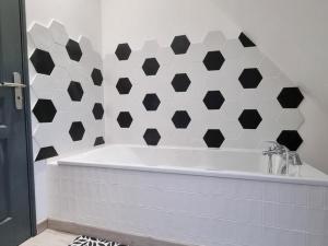 eine Badewanne im Bad mit schwarzen und weißen Fliesen in der Unterkunft Gîte Hasnon, 4 pièces, 6 personnes - FR-1-510-203 in Hasnon