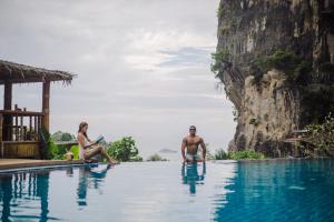 a man and woman sitting in a swimming pool at a resort at Railay Phutawan Resort in Railay Beach