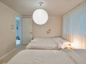 a bedroom with two beds and a large light fixture at Hygge - Urban Hideout with four comfort beds in Seoul