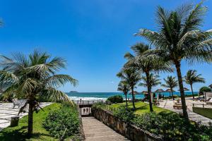 Blick auf einen Strand mit Palmen und das Meer in der Unterkunft Flat vista mar dentro de resort de luxo STO2206 in Florianópolis