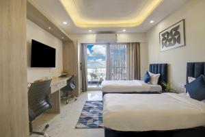 ein Hotelzimmer mit 2 Betten und einem Schreibtisch in der Unterkunft FlxHo Quad - Luxury Studio Apart Hotel DLF Cyber City in Gurgaon