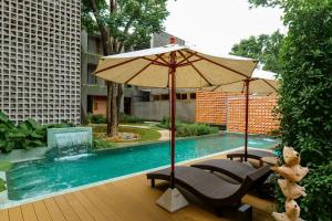 an umbrella and chairs next to a swimming pool at Proud Phu Fah Muang Chiang Mai in Chiang Mai