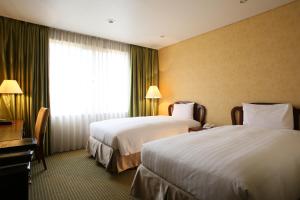 a hotel room with two beds and a window at International Resort Hotel Yurakujo in Narita