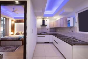 a kitchen with white cabinets and a sink and a bed at Luho C103 in Dehradun