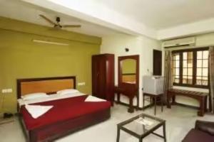 a bedroom with a bed and a living room at Hotel Soorya Inn in Pondicherry