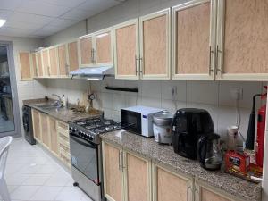 La cuisine est équipée de placards en bois et d'un four avec plaques de cuisson. dans l'établissement Family rooms with beach view, à Ajman