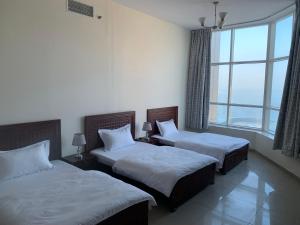 a bedroom with two beds and a large window at Family rooms with beach view in Ajman 