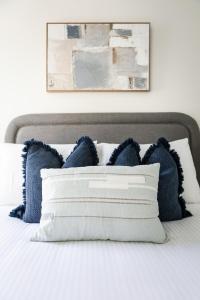 a bed with blue and white pillows on it at Clare St Apartments by Urban Rest in Port Adelaide