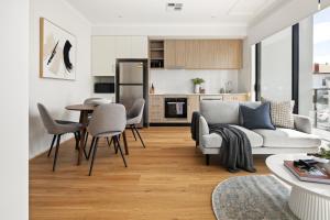 a living room with a couch and a table and chairs at Clare St Apartments by Urban Rest in Port Adelaide