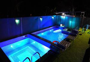 a swimming pool with blue lighting in a backyard at night at Arabian Nights Munnar in Munnar