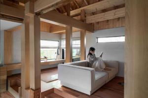 a woman sitting on a couch reading a book at Han Yul Jae - Hanok in Chuncheon
