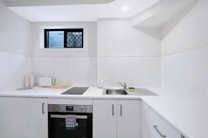 a white kitchen with a sink and a window at The Sunny Studio - A Peaceful Riverside Abode in Brisbane