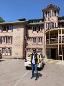 un hombre parado en un estacionamiento frente a un edificio en Hotel Sterling , Srinagar, en Srinagar