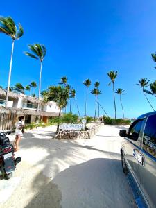 un'auto parcheggiata sulla spiaggia con palme di cozy apartment near the beach los corales punta Cana. a Punta Cana