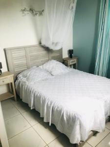 Un dormitorio con una cama blanca con dos mesitas de noche. en Bungalows Mathilde-non fumeur, en Bouillante