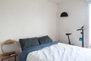 a bedroom with a bed with a blue blanket and a lamp at Luminous cocoon - view of Canal Saint-Martin in Paris
