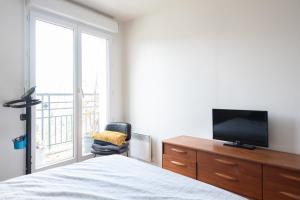 a bedroom with a bed and a tv on a dresser at Luminous cocoon - view of Canal Saint-Martin in Paris