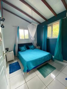 a blue bedroom with a bed and two windows at Bungalows Mathilde-non fumeur in Bouillante