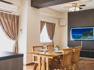 een eetkamer met een tafel en stoelen en een tv bij Comfort Plus in Chatan