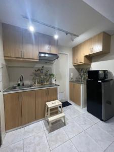 a kitchen with wooden cabinets and a black refrigerator at Pocket Home in Manila
