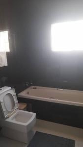 a bathroom with a white toilet and a bath tub at Casa de Amor in Luanda