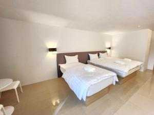 2 camas en una habitación con sábanas blancas en Prom Ratchada Hotel - SHA Plus en Bangkok