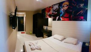 Un dormitorio con una cama blanca y una pintura en la pared en OS Hotel Batu Aji Batam en Batam Centre