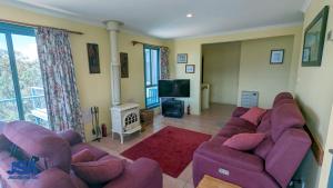 a living room with purple couches and a tv at Naturescape in Jindabyne