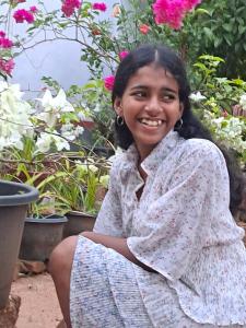 a young girl sitting in front of flowers at Marari Bethsaida Homestay in Shertallai