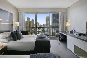 a hotel room with a bed and a desk with a view at Ocean View 2-Bed Studio In the Heart of Surfers in Gold Coast