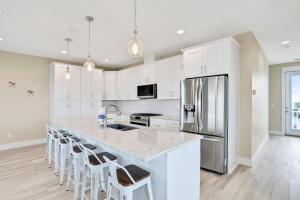 a kitchen with white cabinets and a large island with bar stools at The Minty Pearl in Mexico Beach