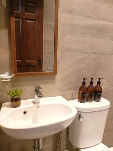 a bathroom with a sink and a toilet with three bottles on it at JD&S Apartments Unit 4 in Iligan City