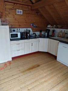 a kitchen with white cabinets and a wooden floor at Marmotte 2 in Ornon