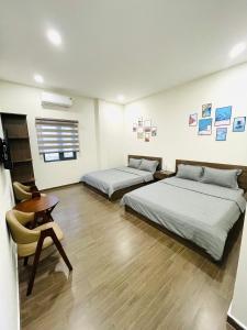 a room with two beds and a table and a chair at Rio Guest House - Phú Quốc in Phú Quốc