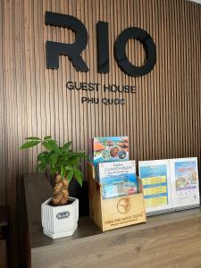 a shelf with books and a potted plant and a sign at Rio Guest House - Phú Quốc in Phú Quốc