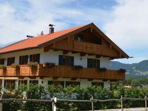 a building with a wooden roof and a fence at Lovely apartment in Gaißach in Gaißach