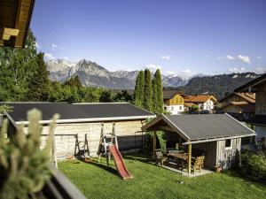 um quintal com uma casa com um parque infantil e montanhas em Cosy apartment in Bolsterlang em Bolsterlang