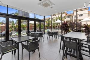 an empty restaurant with tables and chairs and windows at Ultra Broadbeach in Gold Coast