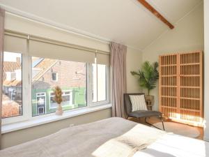 a bedroom with a large window and a chair at Lovely holiday home with garden in Vrouwenpolder