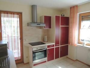 - une cuisine avec des placards rouges et une cuisinière dans l'établissement Apartment 2 Mainblick Brigitte, 