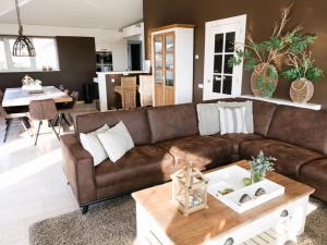 a living room with a brown couch and a table at Holiday home Zanddrijver in Makkum