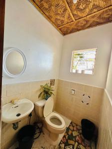 a bathroom with a toilet and a sink at Playa del Fuego Camiguin Beach Hostel & Resort in Mambajao