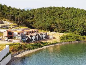 ein Haus auf einem Hügel neben einem Wasserkörper in der Unterkunft Gyeongnam goseong Hotel With7 in Goseong