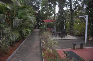 um parque com um banco e mesas e árvores em Shilaj em Dapoli